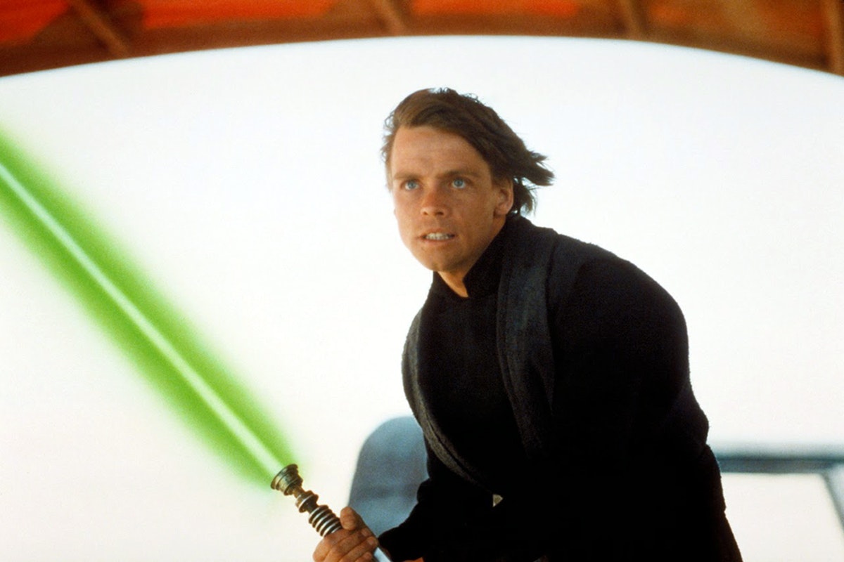 Luke Skywalker with black robes on holding an ignited green lightsaber on Tattooine
