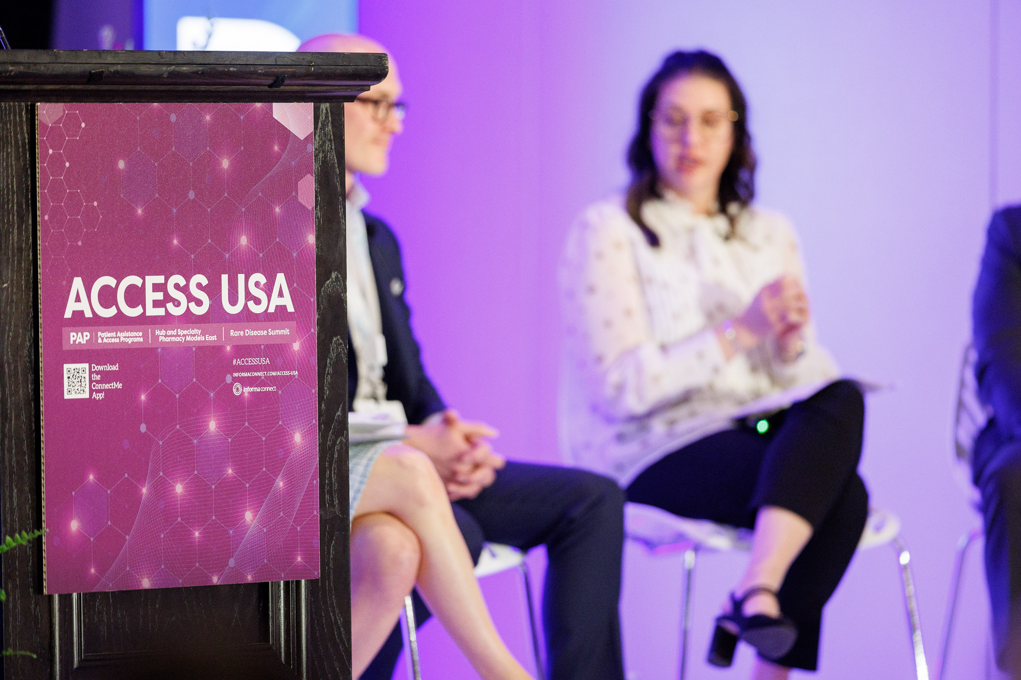 Access USA logo on a podium with speakers on stage behind it