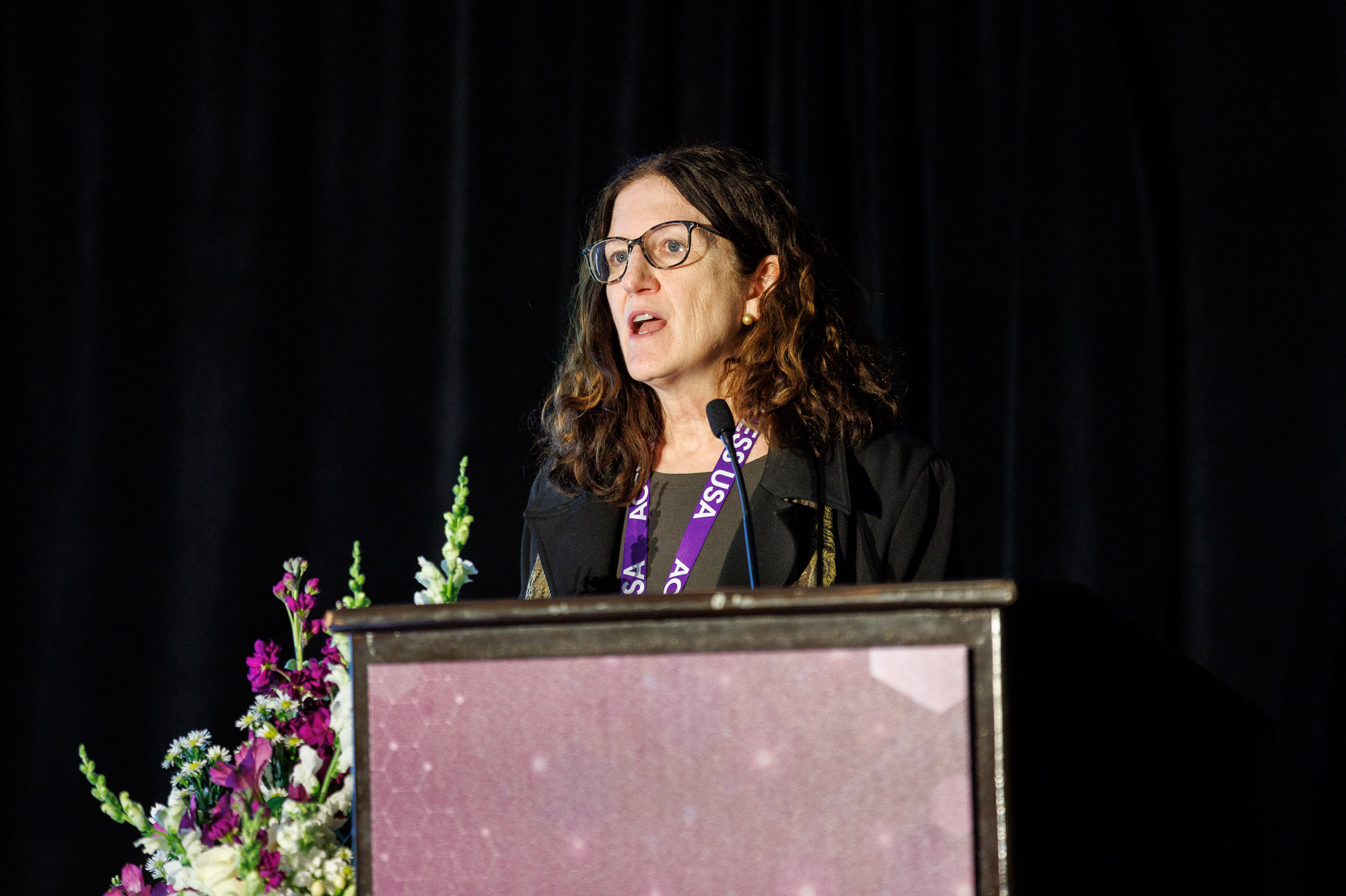 A speaker addresses the audience on the podium at Access USA