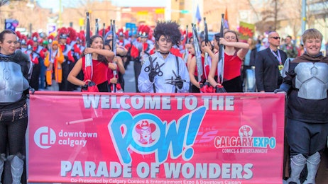 The mayor poses in cosplay behind the POW Parade sign