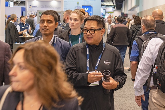 A large crowd of diverse attendees mingling at a bustling convention center