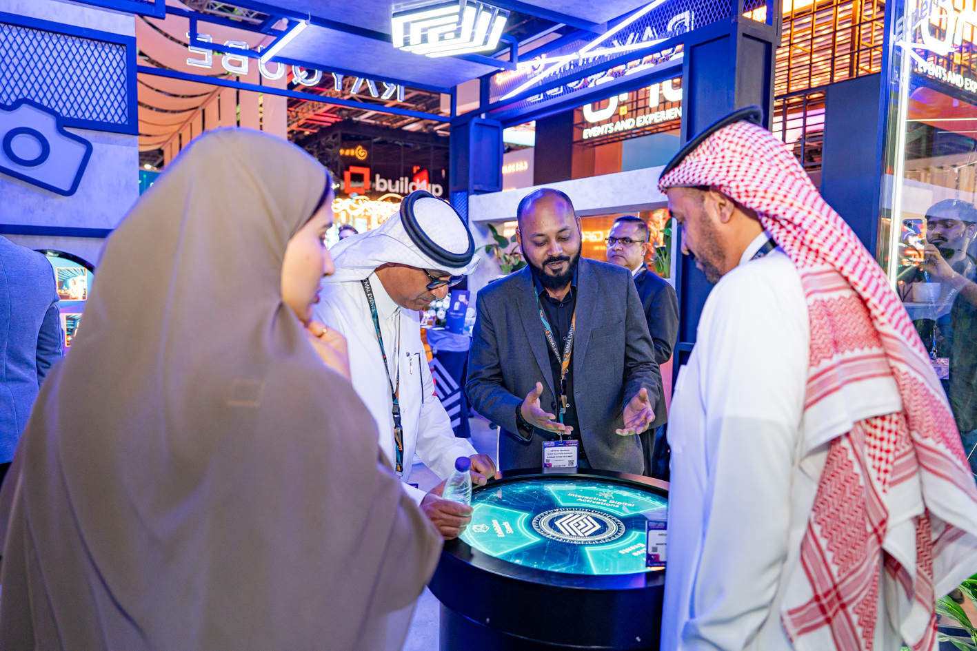Two event professionals networking on the MEES 2025 show floor surrounded by exhibition stands and attendees