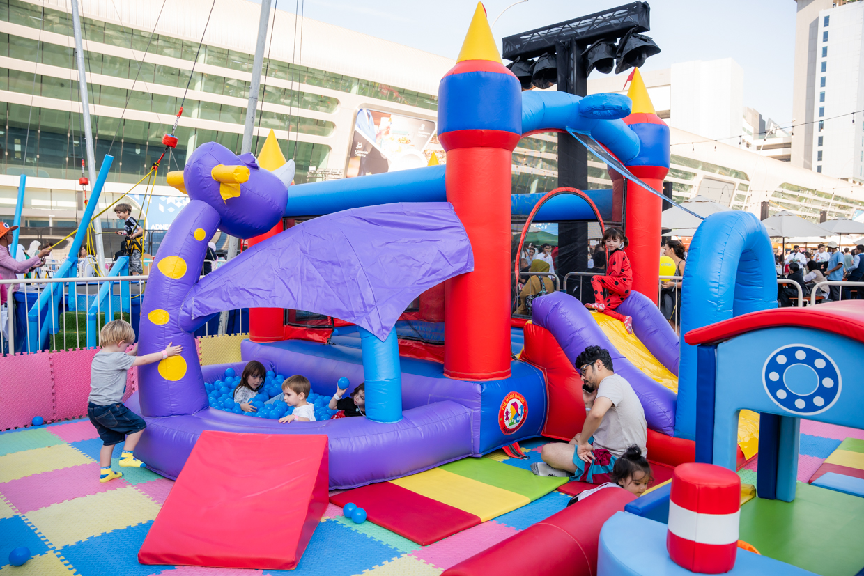 Children playing on colourful inflatables in the MEFCC Kids Zone, enjoying family-friendly activities at the outdoor Festival Plaza.