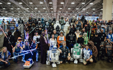 Large group of Star Wars cosplayers and droids posing for a big group photo.