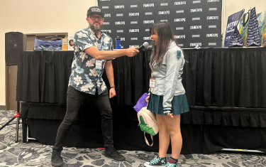 a man holding a microphone (left) towards a young girl (right) screaming as part of the Scream Supreme Competition.