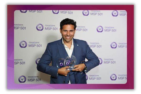 A photo of a man smiling for the camera and holding three awards in his hands