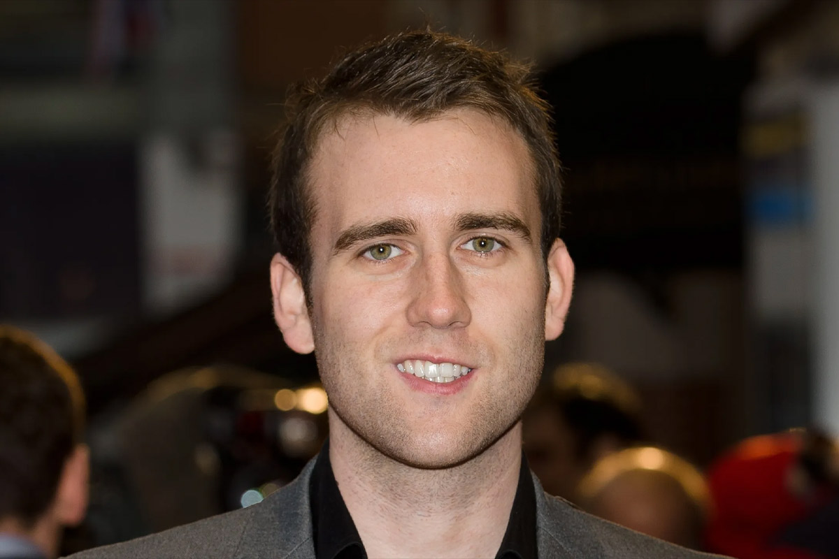 Matthew Lewis smiles at the camera wearing a grey suit