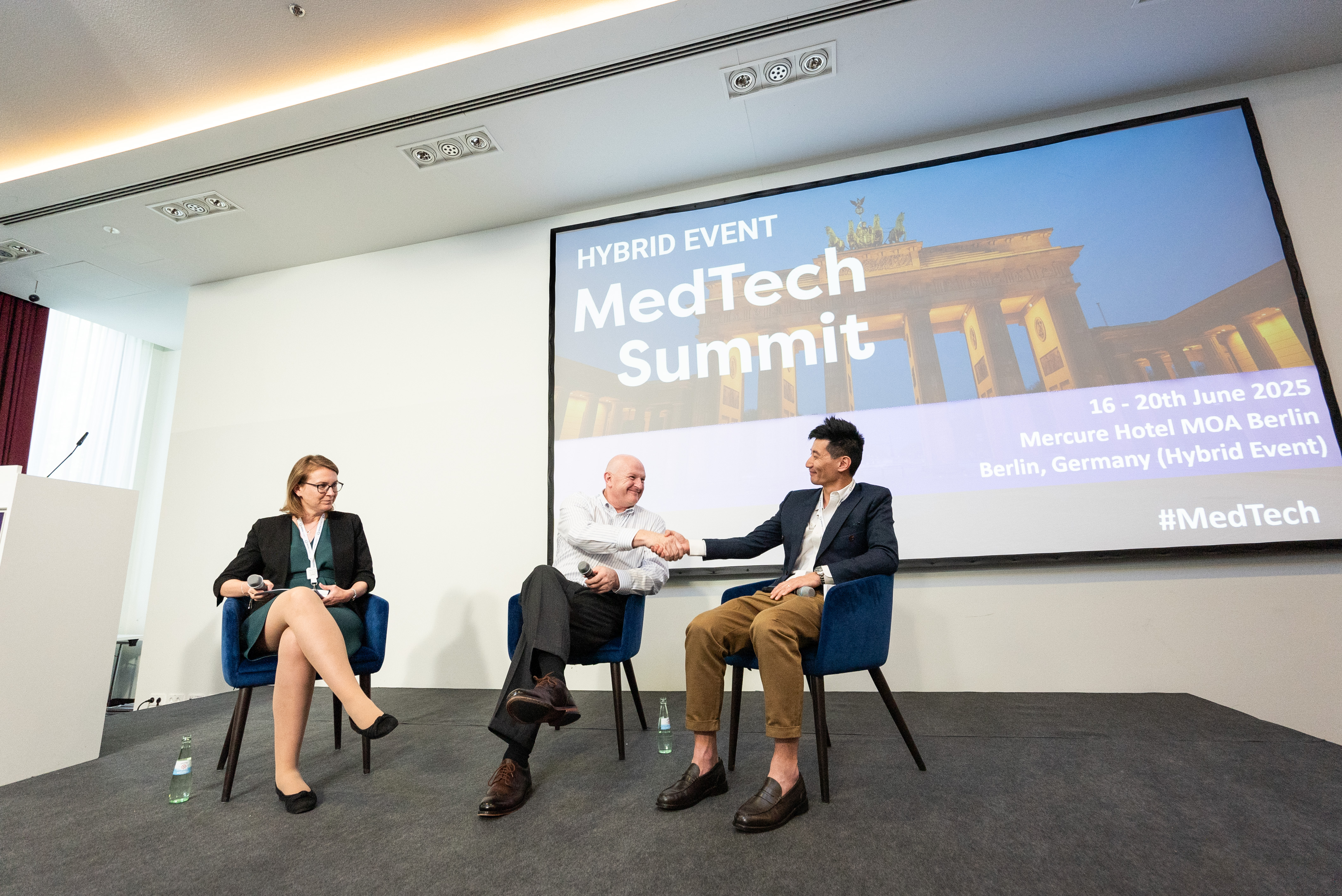 Speakers exchange a firm handshake, concluding their impactful session with mutual respect and appreciation.