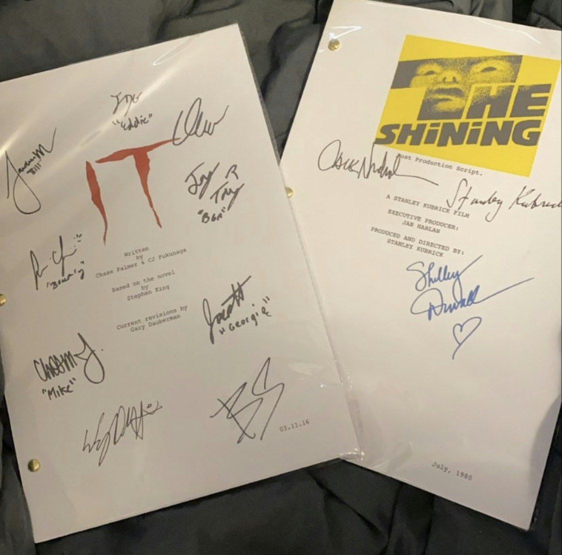 Two white movie documents with multiple signatures on the front of them lay on top of a grey colored background.