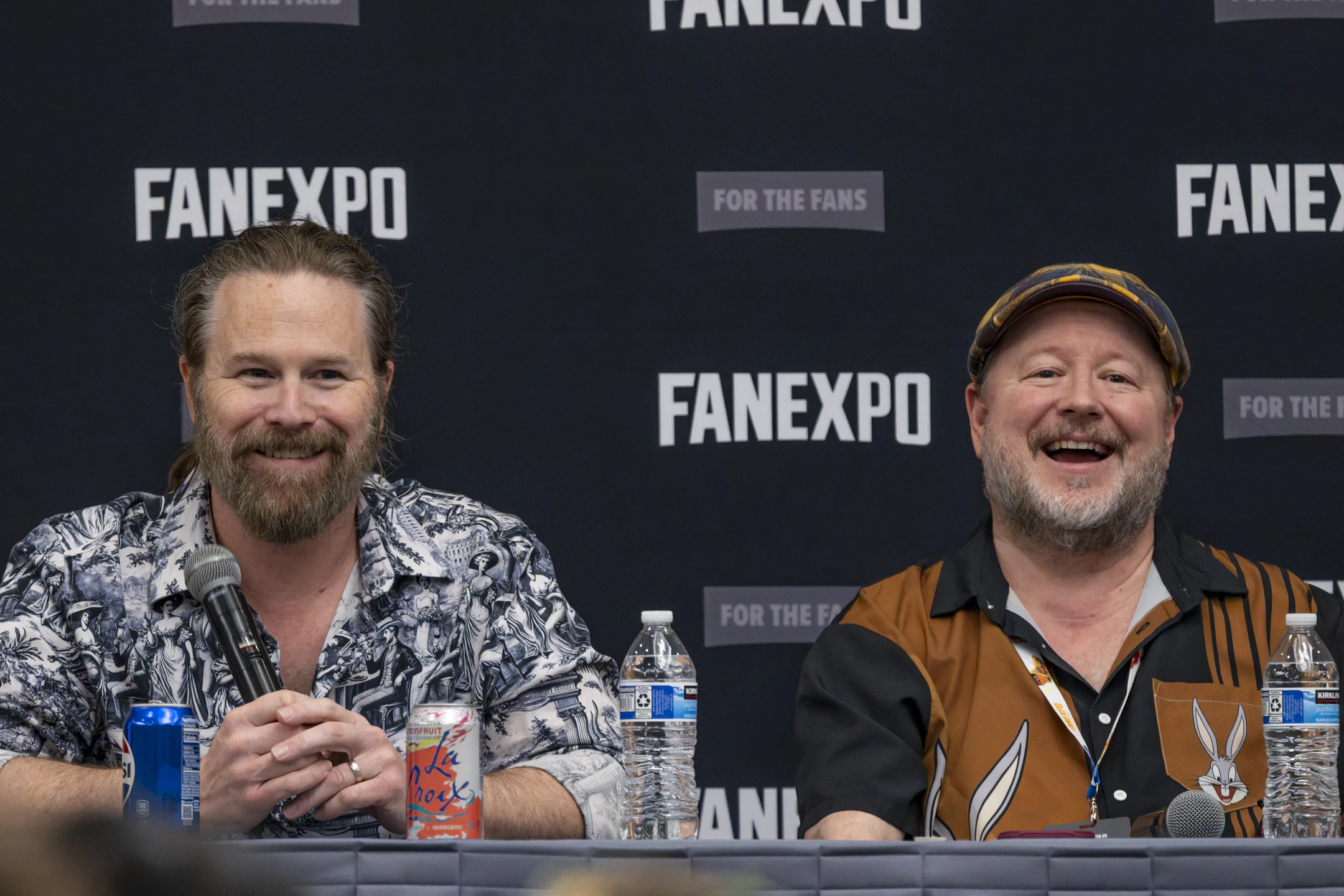 Six cast members from My Hero Academia sit side by side on stage, smiling and interacting with the crowd during their panel.