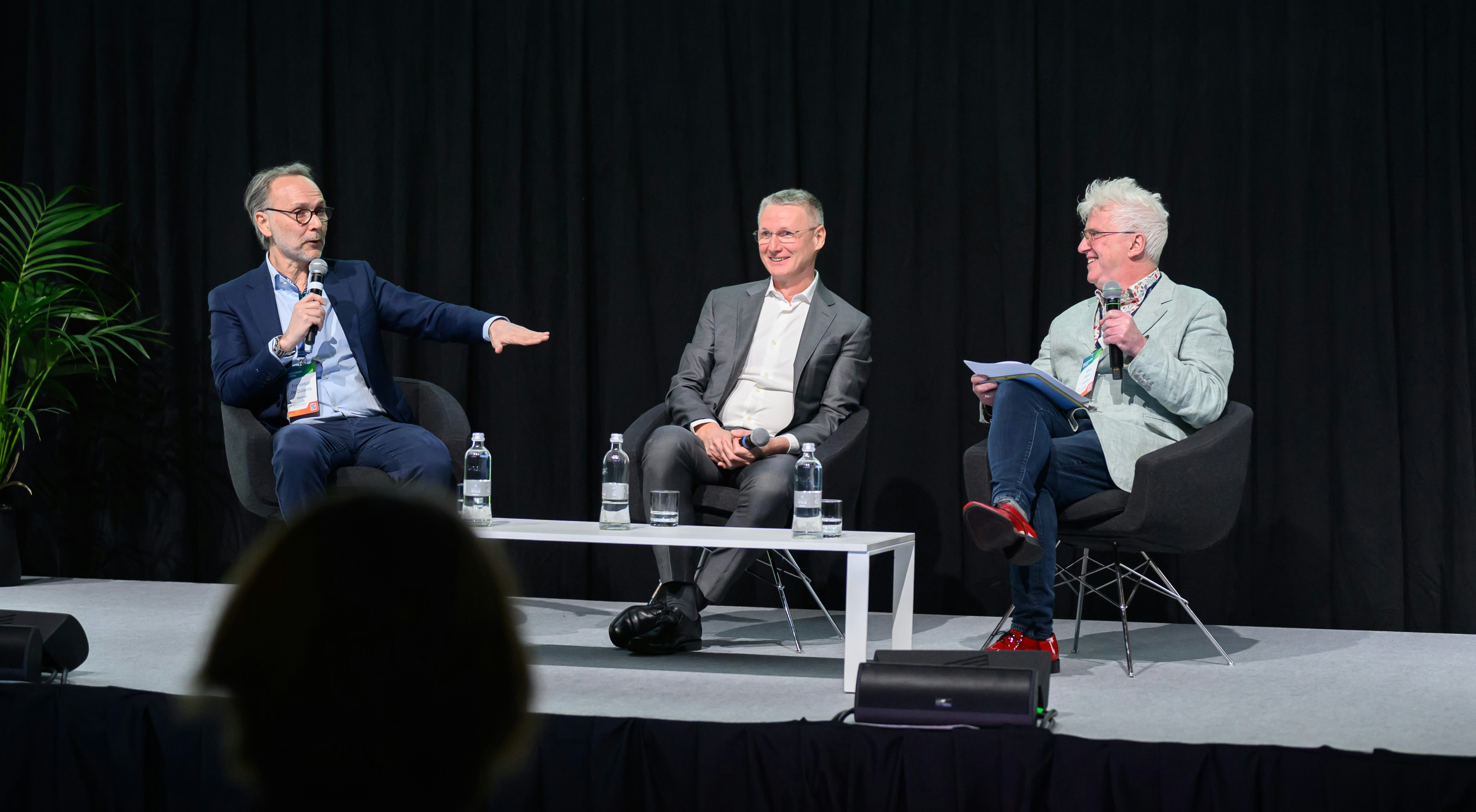 Three speakers on the stage having a discussion
