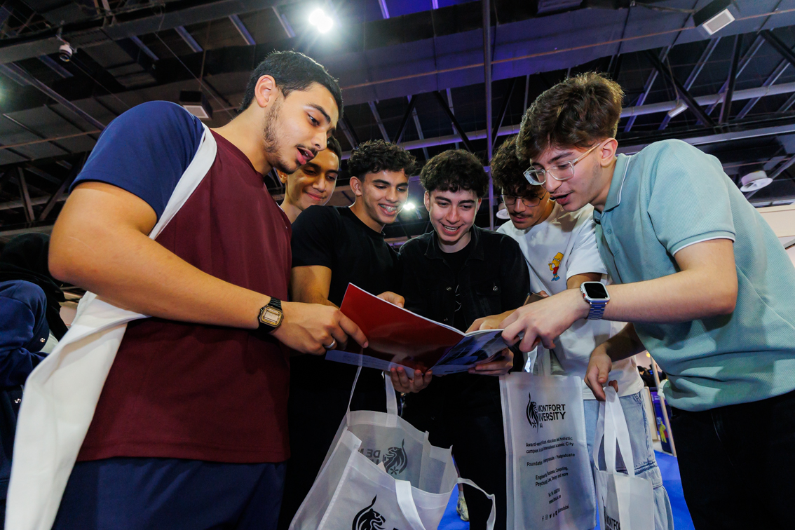 Group of students review brochures and programmes from global institutions at Najah Dubai university fair.