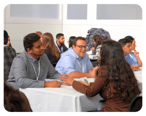 A group of people engaged in conversation while sitting around a table at a networking event