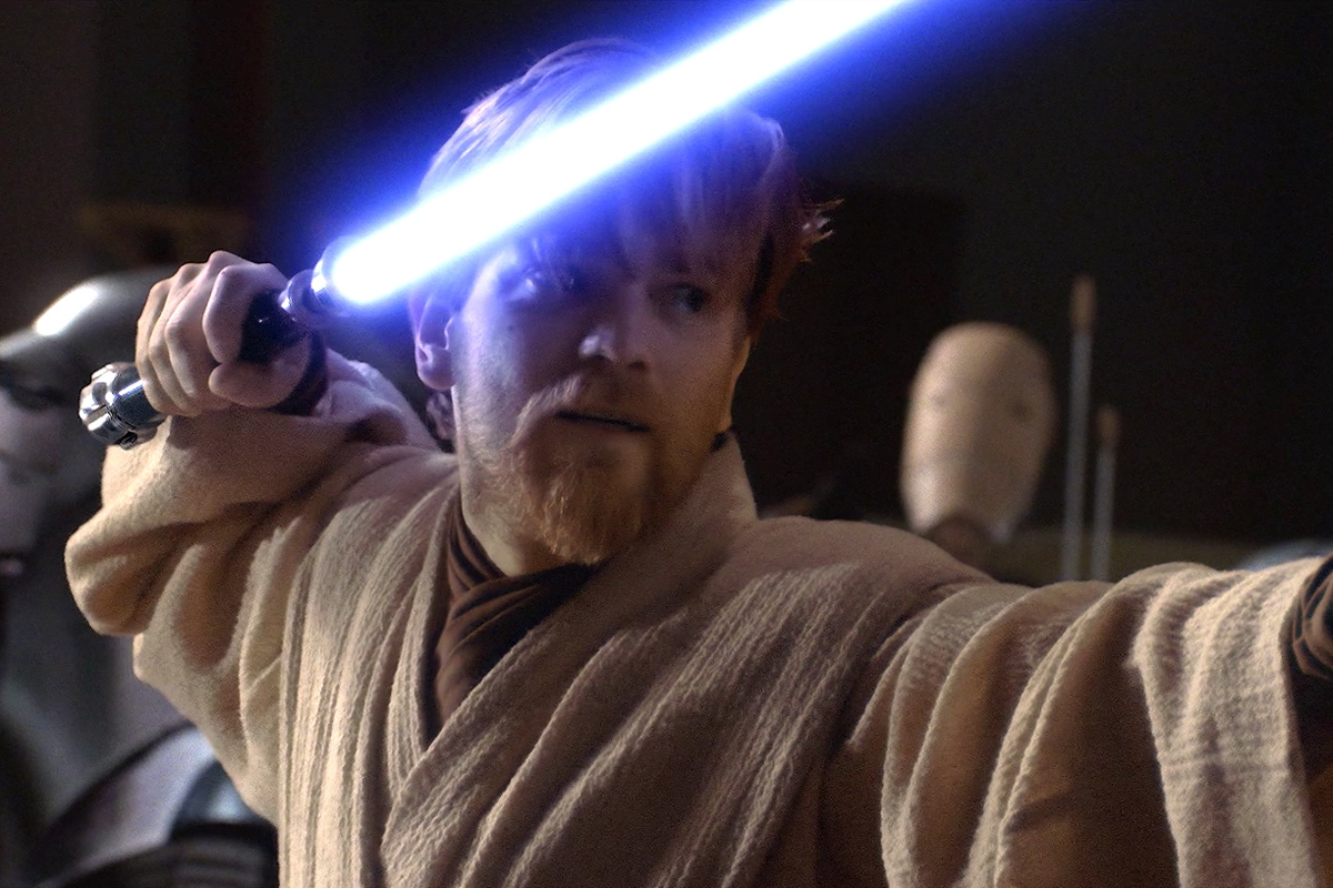 Obi-Wan Kenobi holding an ignited blue lightsaber with brown robes on standing in a fighting pose