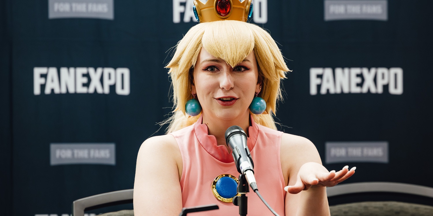 A cosplayer dressed as Princess Peach speaks into a microphone during a fan-led panel at Dallas FAN FESTIVAL, with a FAN EXPO backdrop behind her.