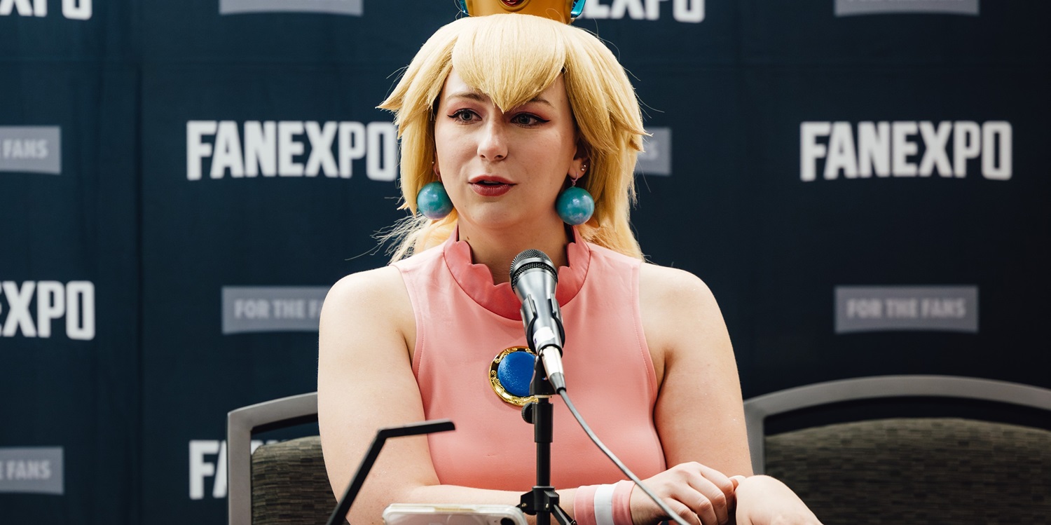 A cosplayer dressed as Princess Peach speaks into a microphone at a panel during Dallas FAN FESTIVAL. The FAN EXPO branding can be seen behind her.