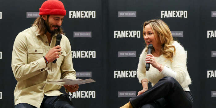 Tara Strong (right) laughs as her partner (left) asks fan questions from the list in his hands.