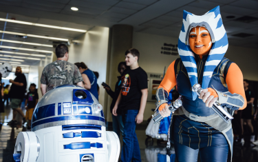 an R2-D2 droid (left) and Ashoka cosplayer (right) posing for a photo.