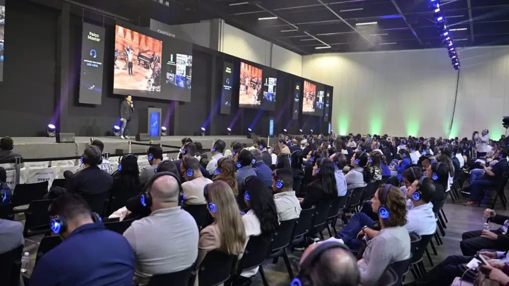 Plateia usando fones de ouvidor com iluminação azul assiste a palestrante no Palco Master do HIS - Healthcare Innovation Show.