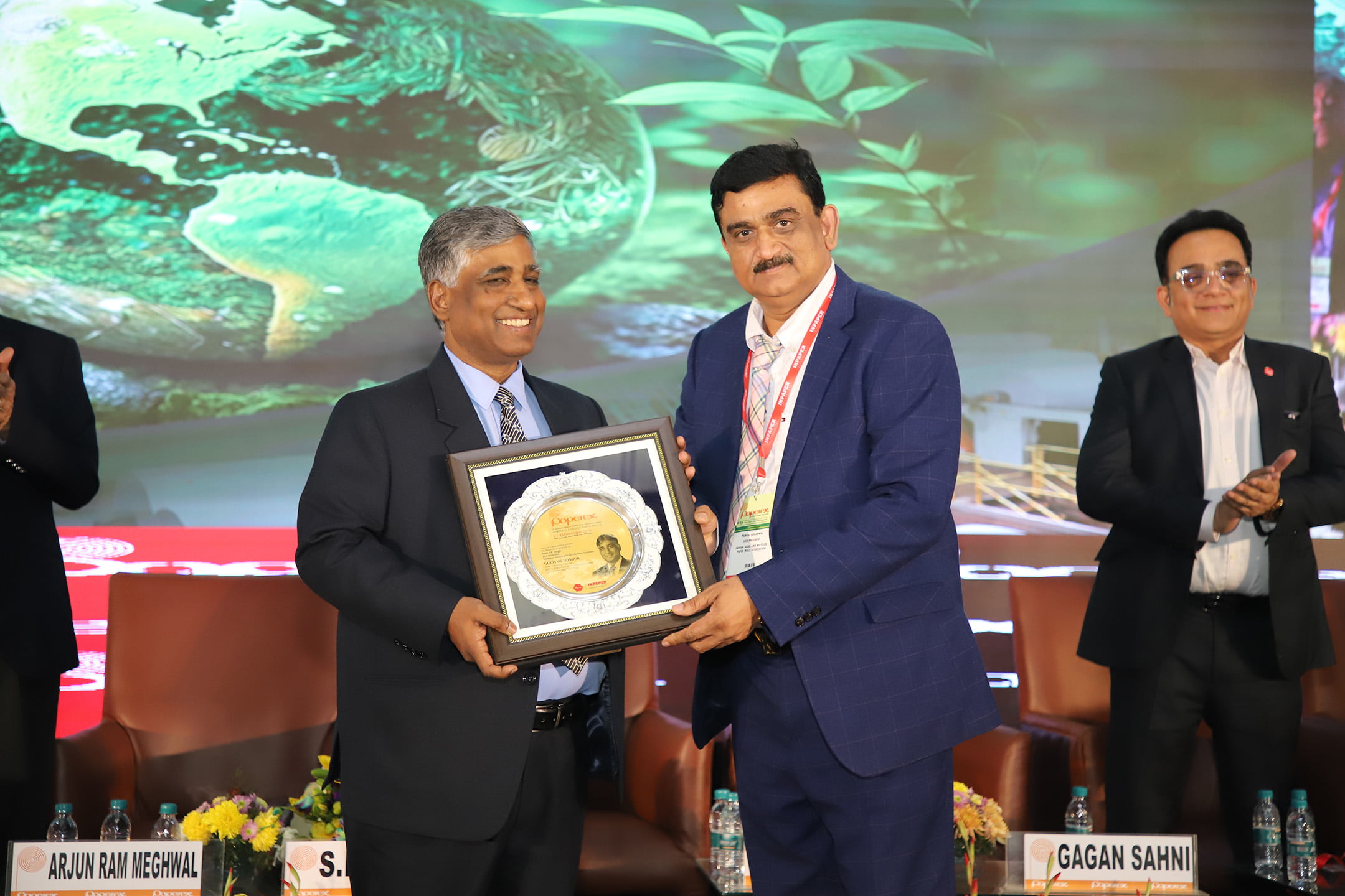Two men in suits holding an award during the ceremony on stage