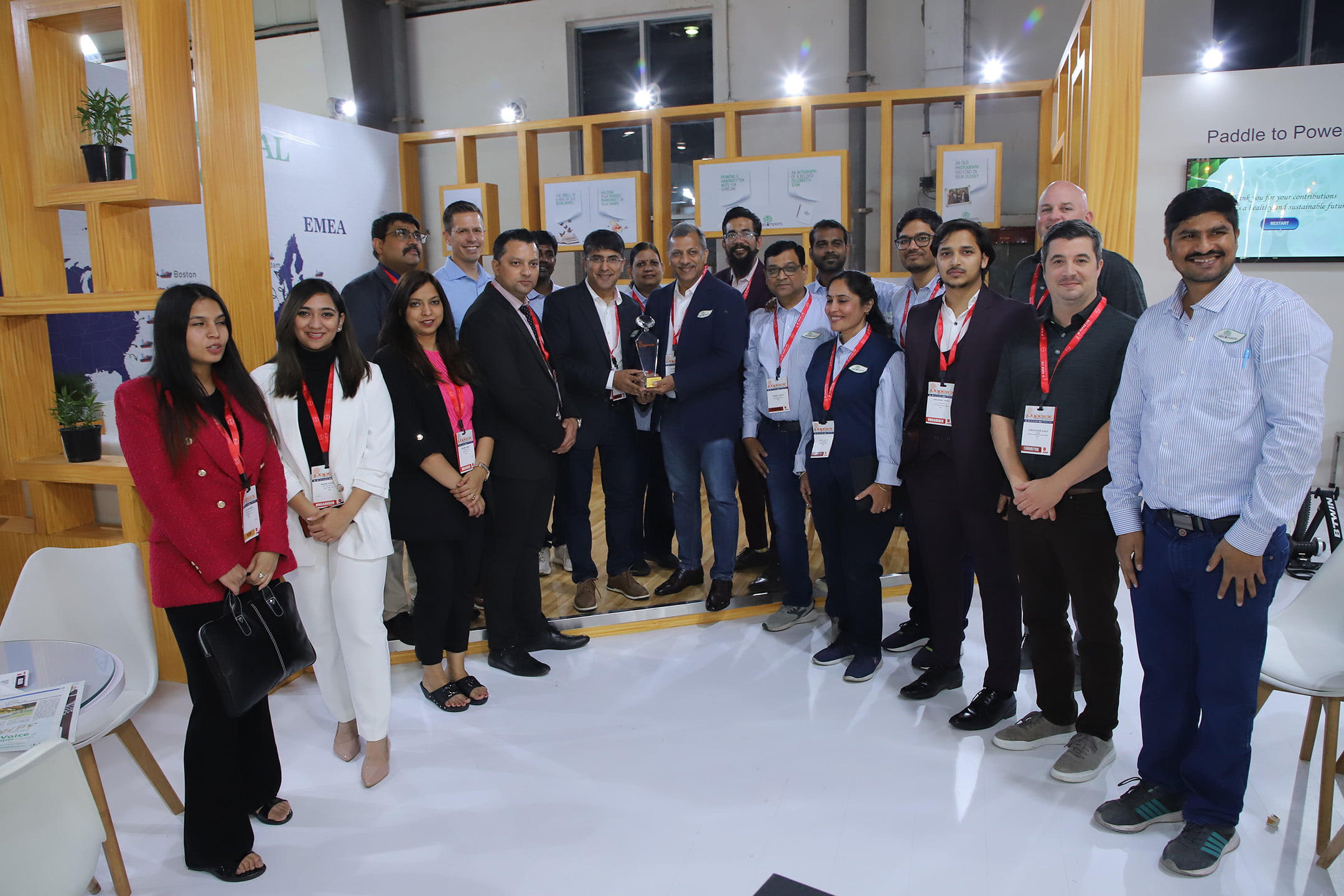 Group of professionals posing with an award at an exhibition booth