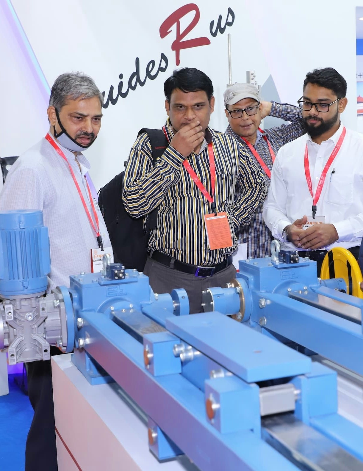 Group of professionals examining industrial machinery at a trade exhibition.