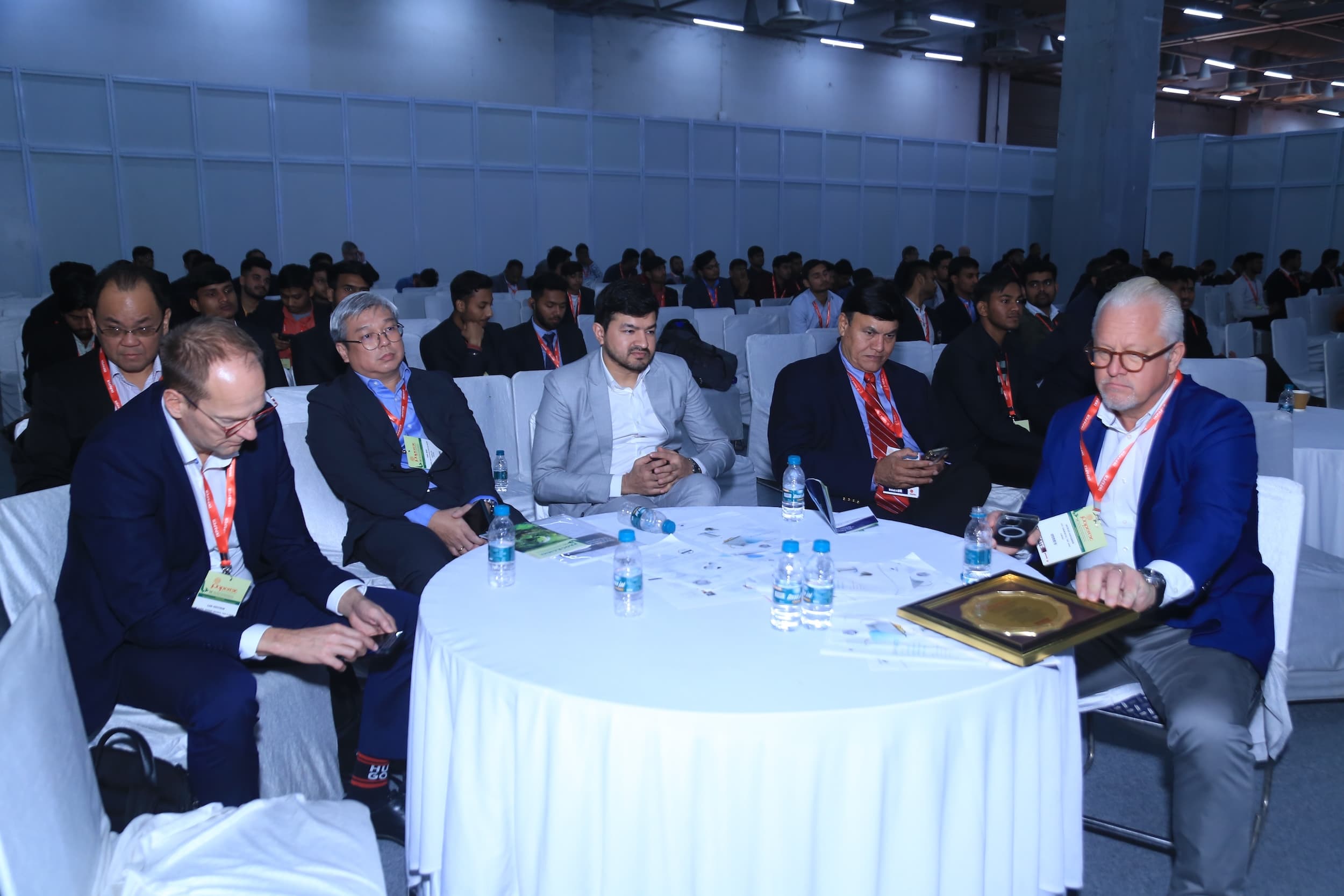 Business conference attendees seated at round tables in a large convention hall.