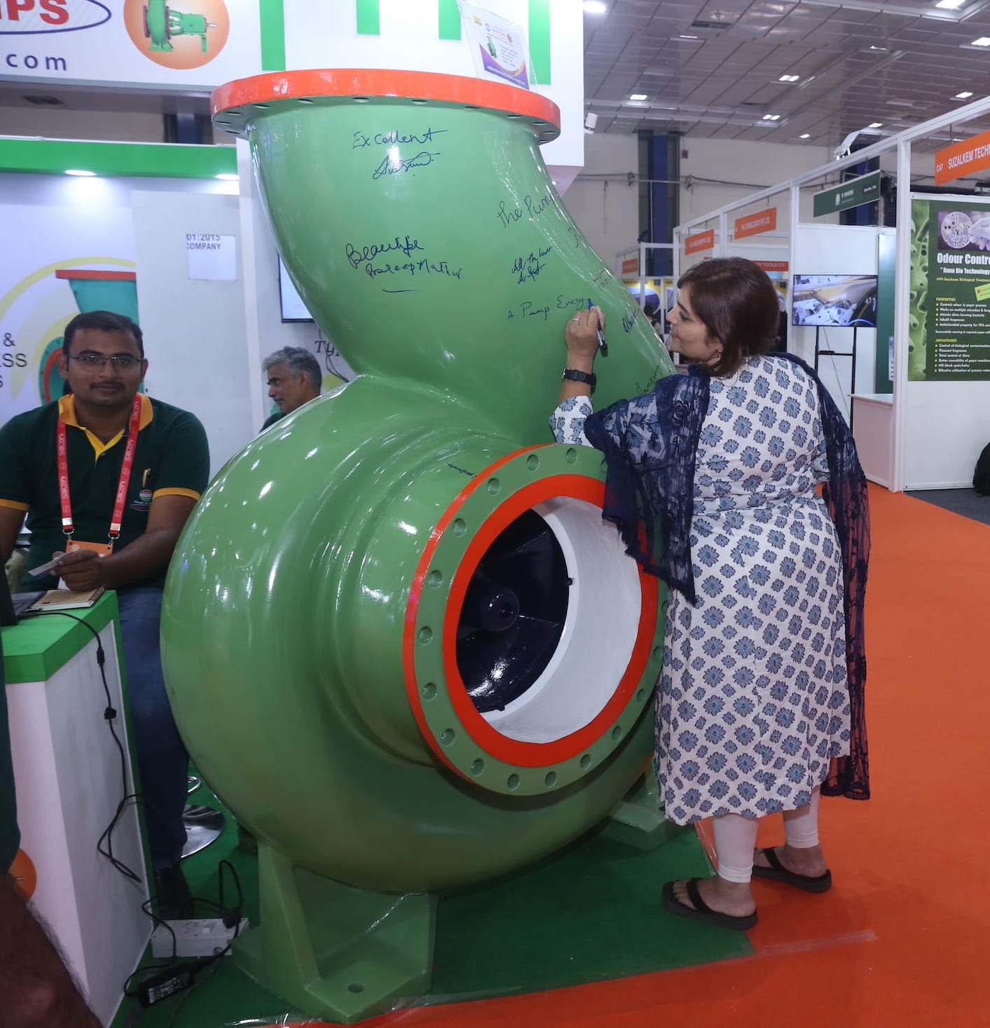 Attendee stamping or marking a large green industrial machine at Paperex South India as part of the exhibition experience.