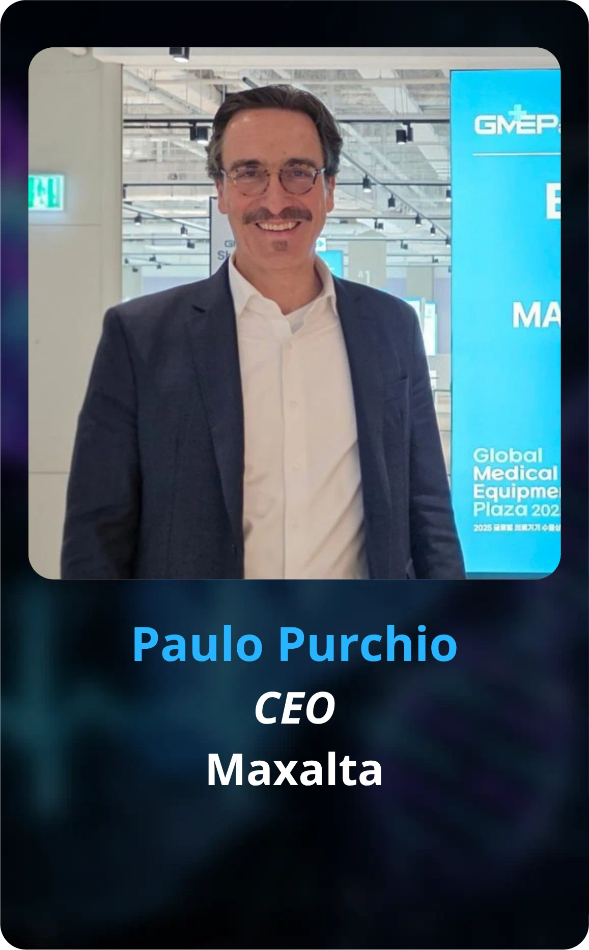 Paulo Purchio, CEO da Maxalta, palestrante do Healthcare Innovation Show (HIS). Homem sorrindo, com bigode, óculos, blazer escuro e camisa branca.