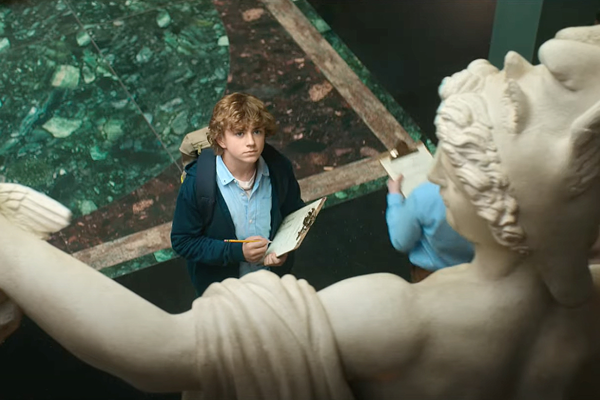Percy Jackson looks up at a statue in a museum