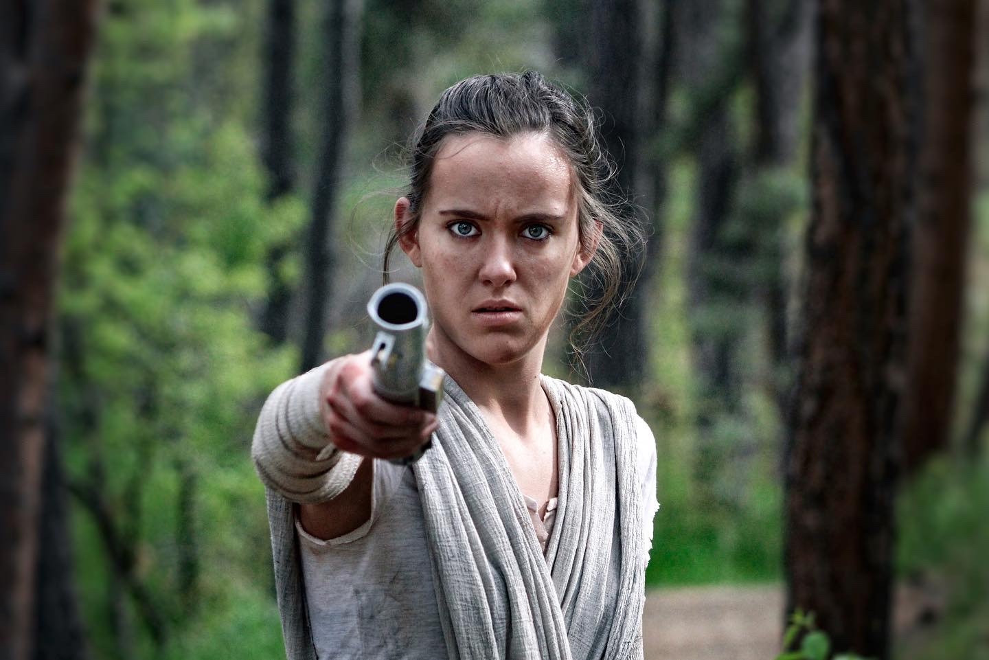 Cosplayer dressed as Rey from The Force Awakens and holding a lightsaber