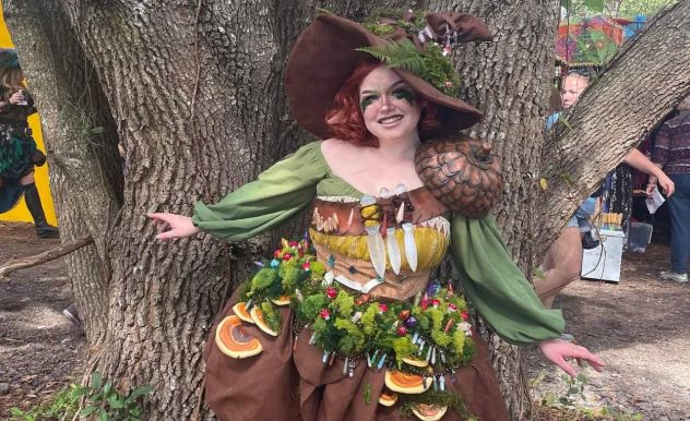 Emma Rubini in cosplay posing next to a large tree