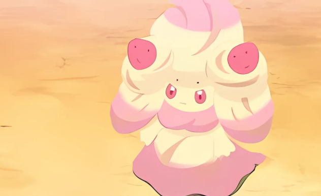 Alcremie stands in the sand, they are straight upright and look disgruntled