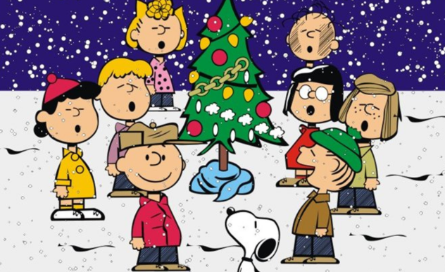 Charlie Brown and friends stand around the tree, singing Christmas carols