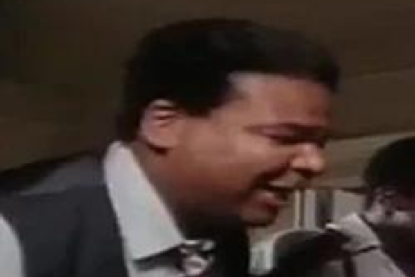 man in suit leaning into microphone