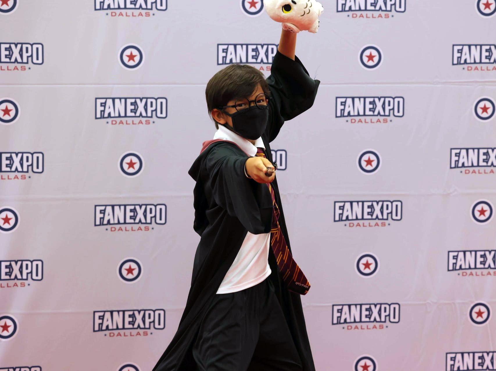 A child cosplays as Harry Potter with his wand facing the camera on the Cosplay Red Carpet
