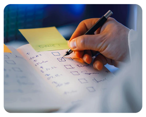 A hand writing on a checklist, indicating tasks being completed or organized.