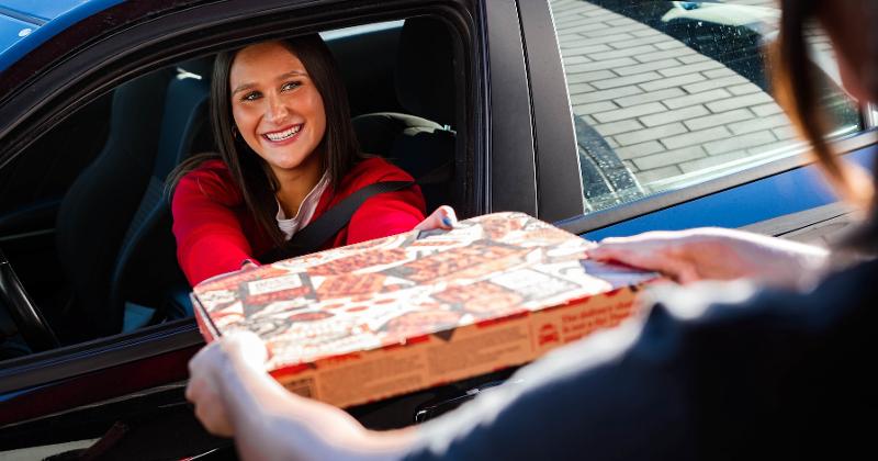 Customer receives pizza box at delivery window