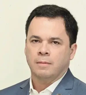 Retrato de Sonia Poloni, CEO da ABCIS. Uma mulher de cabelos longos e escuros, sorrindo, vestindo um blazer escuro com estampa sutil de risca de giz sobre uma camisa social clara.