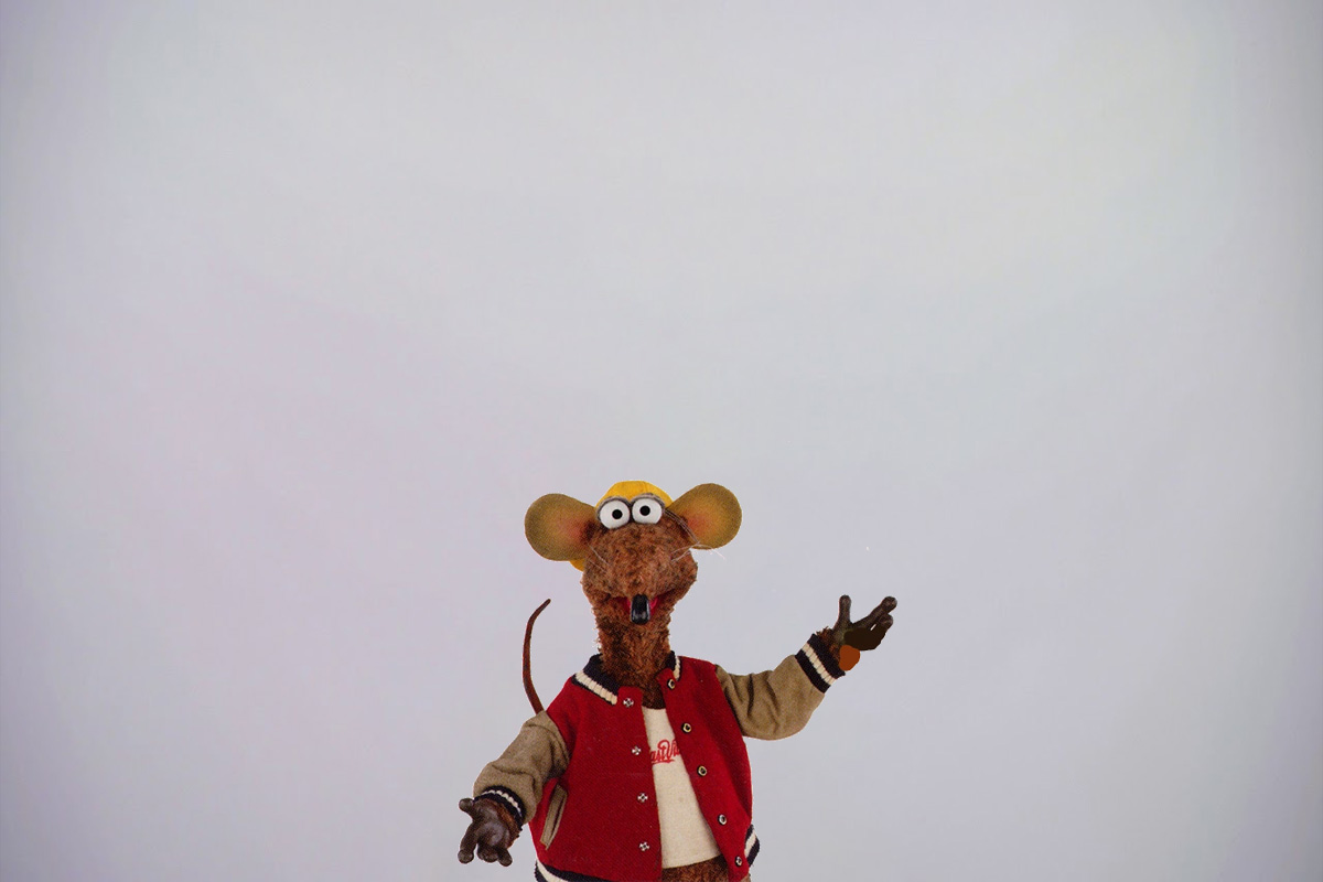 Muppet character Rizzo the Rat standing in a red jacket with his arms outstretched