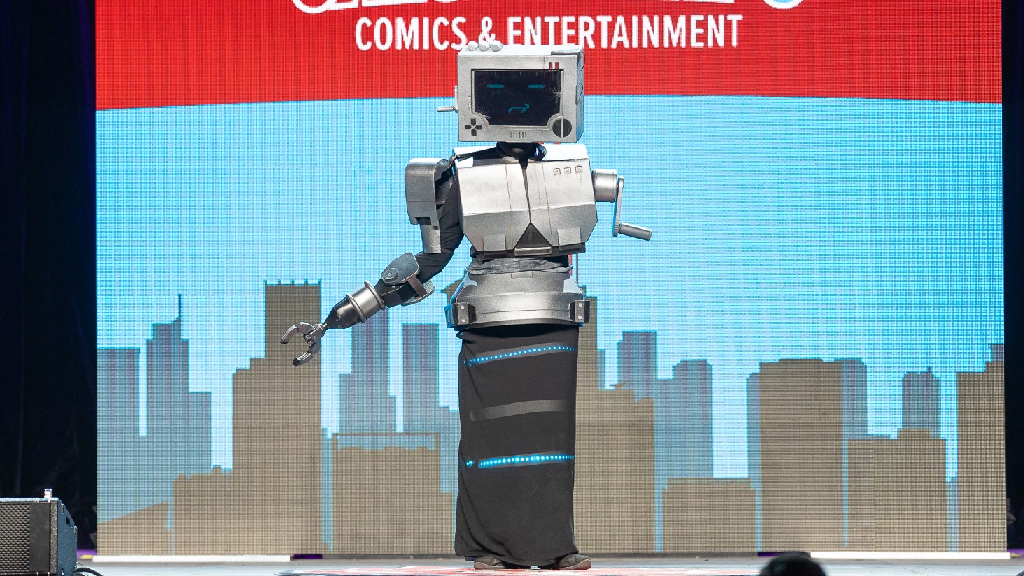 A contestant cosplaying P03 from Inscryption stands onstage