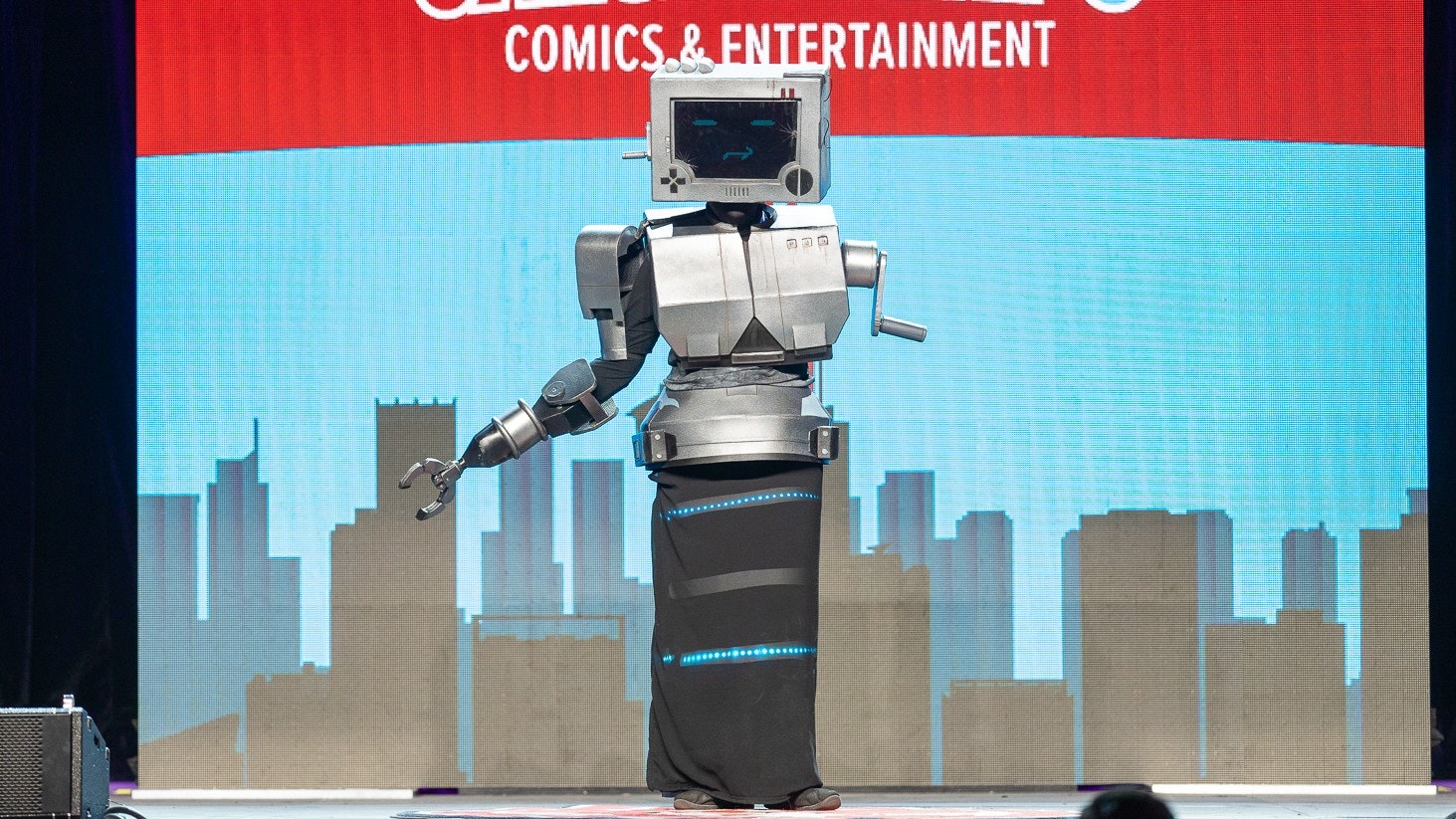 A contestant cosplaying P03 from Inscryption stands onstage