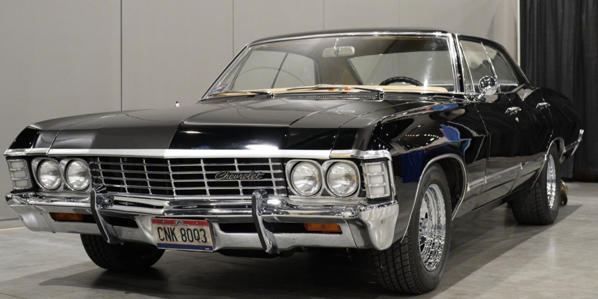 A black 1967 Chevrolet Impala replica from Supernatural is displayed indoors at FAN EXPO Cleveland, shown from the front with chrome details, headlights, and license plate clearly visible.
