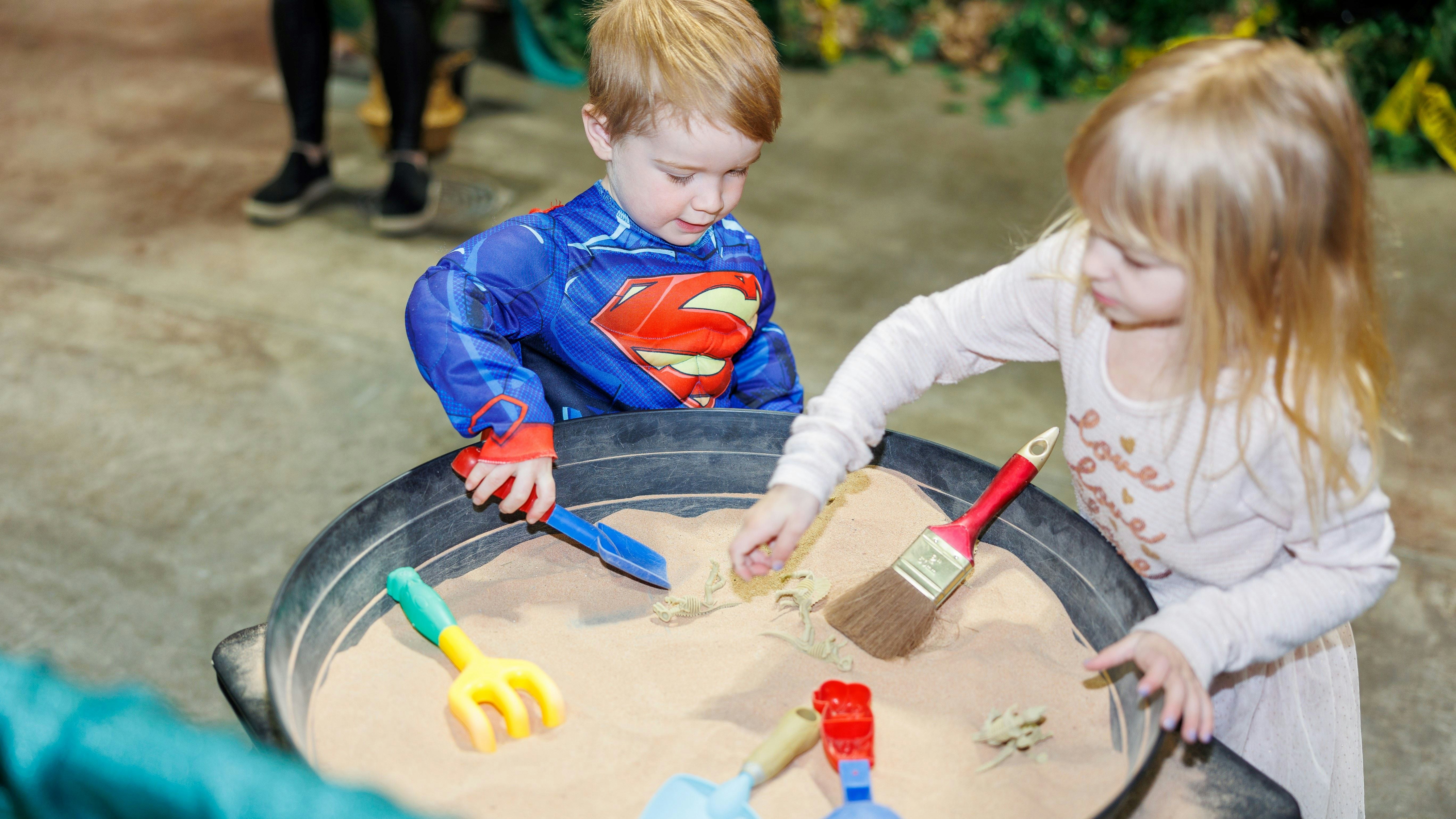 Two kids are playing with sand and shovels in the family zone