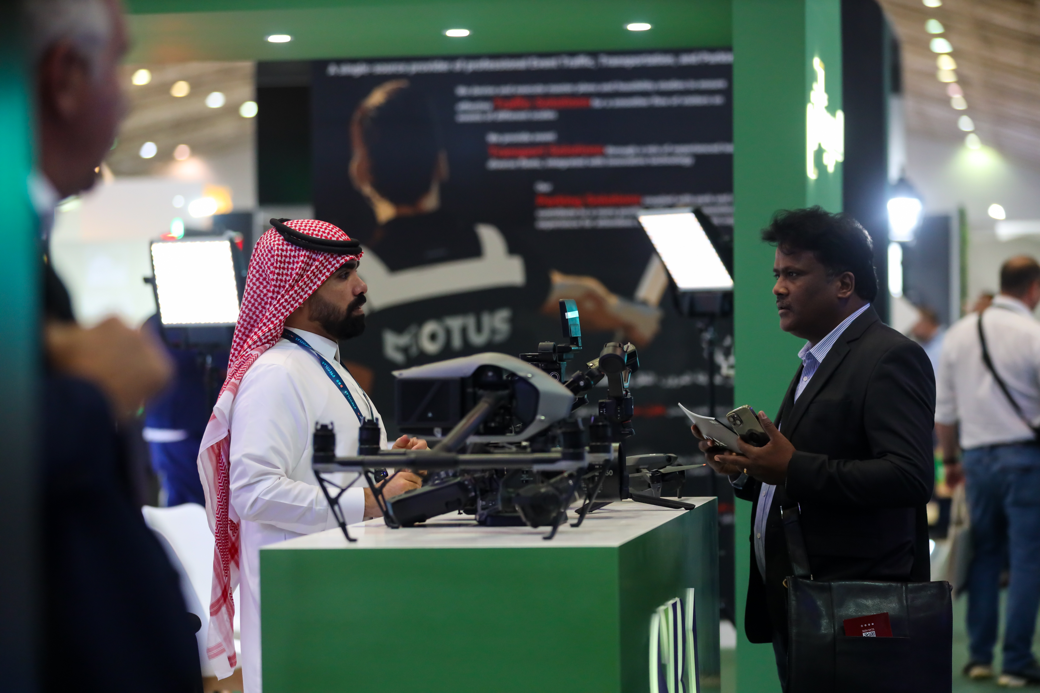Two men discussing drone equipment at a exhibition booth.
