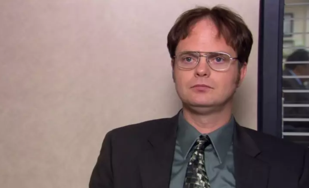 With a serious look, Dwight sits in the interview office and stares at the camera crew off screen.