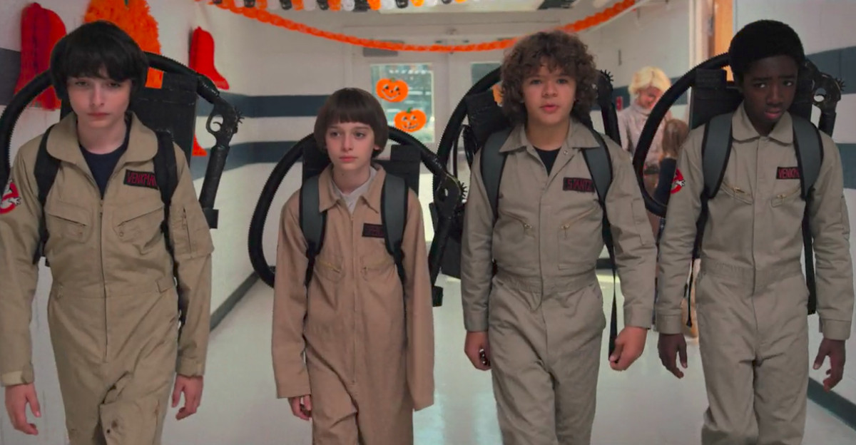 Mike, Will, Dustin, and Lucas walk the school hallway - the four young protagonists dressed as Ghostbusters.