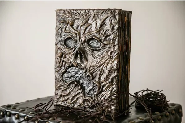 A old book with a scary face on the front of its textured cover