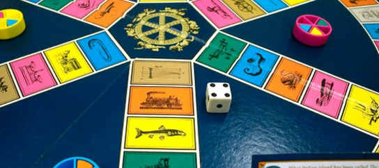 A game of trivial pursuit in play. The die is turned up to 4 with the 1 facing the camera. Each player has a pink and blue wedge, and one one the players has an additional wedge that is yellow.