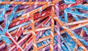 A pile of paper wrapped pixy stix in various flavours and colours. The pile contains red, orange, purple, and blue.
